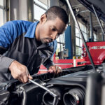 Ford service technician working under the hood of a car